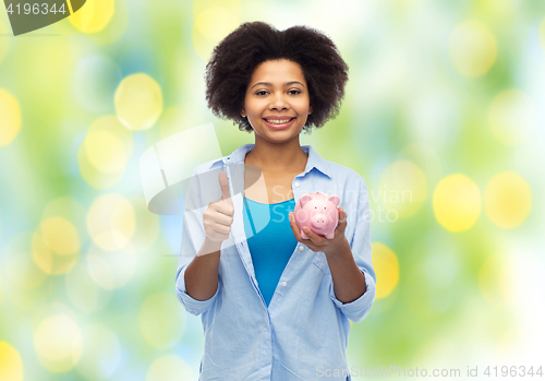 Image of happy woman with piggy bank showing thumbs up