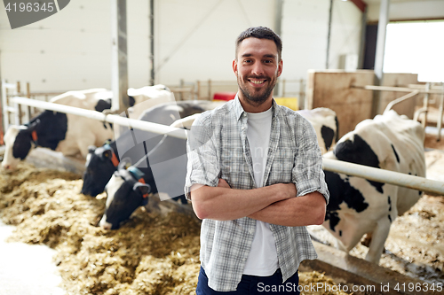 Image of man or farmer with cows in cowshed on dairy farm