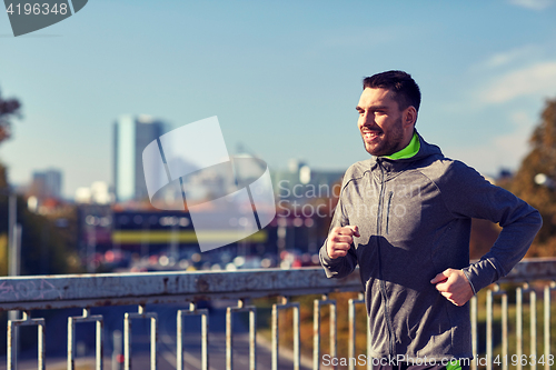 Image of happy young man running over city bridge