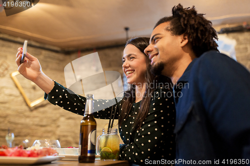 Image of happy couple taking selfie at cafe or bar