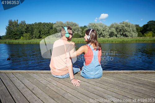 Image of teenage couple with headphones on river berth