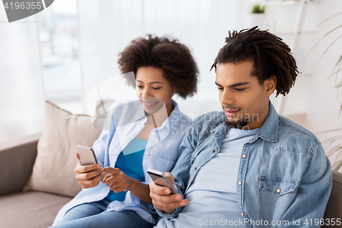 Image of happy couple with smartphones at home