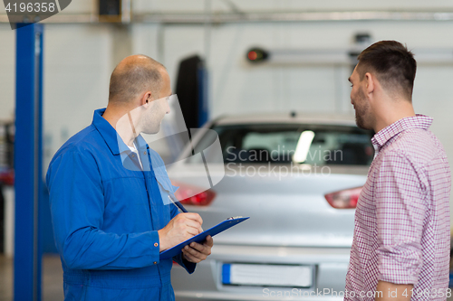 Image of auto mechanic with clipboard and man at car shop