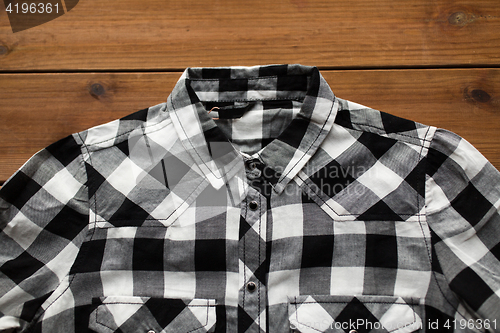 Image of close up of checkered shirt on wooden background