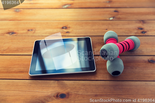 Image of close up of dumbbells and tablet pc on wood