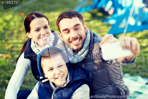 Image of family with smartphone taking selfie at campsite