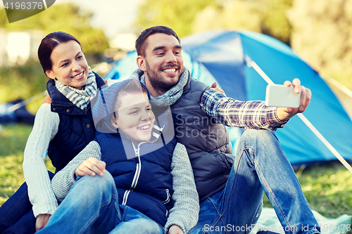 Image of family with smartphone taking selfie at campsite