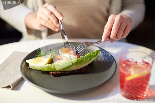 Image of woman eating caviar toast skagen at restaurant