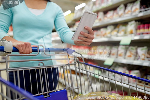 Image of woman with food in shopping cart at supermarket