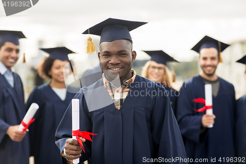 Image of happy students in mortar boards with diplomas