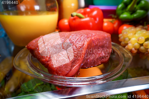 Image of Fresh raw meat on a shelf open refrigerator