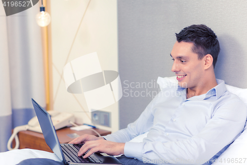 Image of happy businesswoman with laptop in hotel room