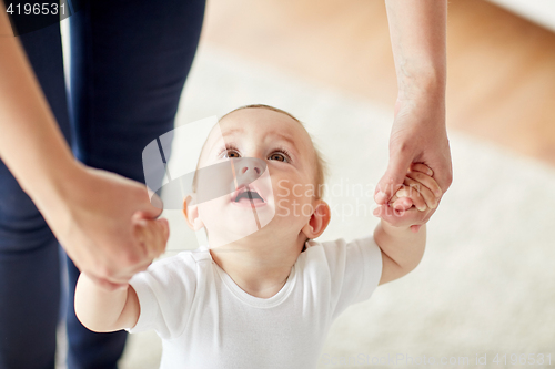 Image of happy baby learning to walk with mother help