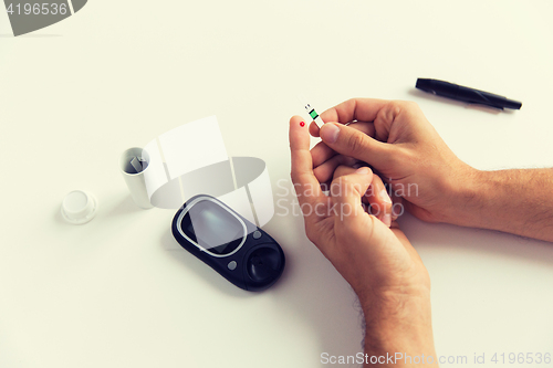 Image of close up of man checking blood sugar by glucometer