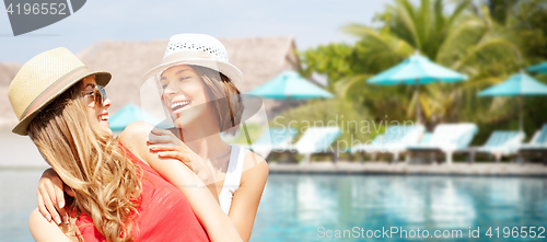 Image of smiling young women in hats on beach