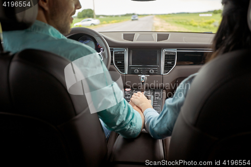 Image of happy couple driving in car and holding hands