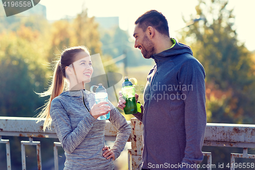 Image of smiling couple with bottles of water outdoors