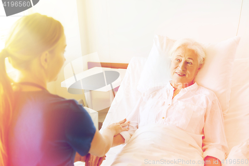 Image of doctor or nurse visiting senior woman at hospital