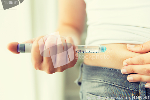 Image of close up of hands making injection by insulin pen
