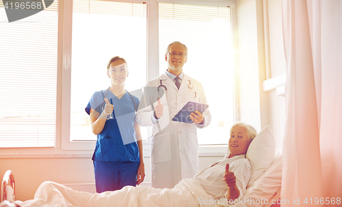 Image of doctor and nurse visiting senior woman at hospital