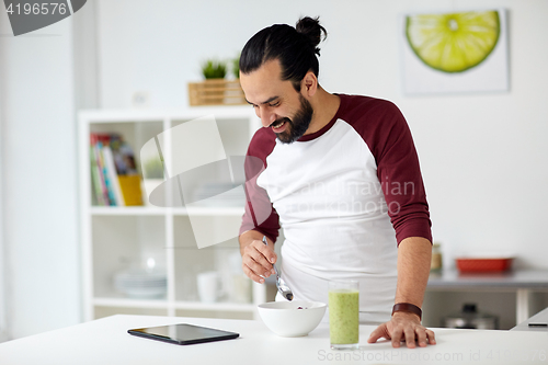 Image of man with tablet pc eating breakfast at home