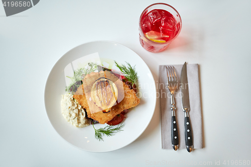 Image of fish salad and glass of drink on restaurant table 