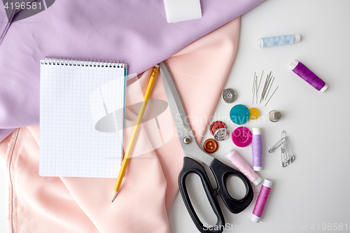 Image of scissors, sewing tools, cloth and notepad