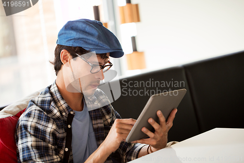 Image of man with tablet pc sitting at cafe table