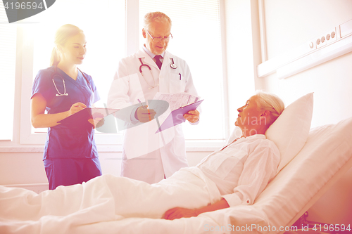 Image of doctor and nurse visiting senior woman at hospital