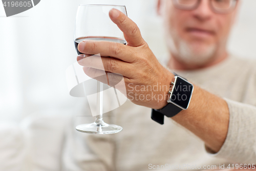 Image of senior man drinking red wine from glass at home