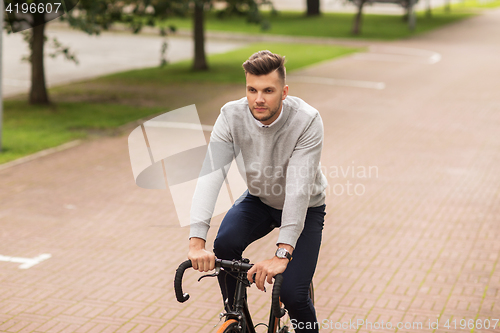 Image of young man riding bicycle on city street