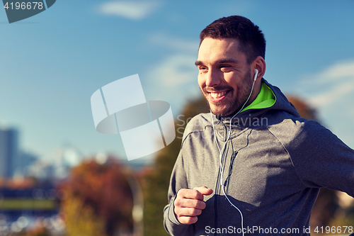 Image of happy man with earphones running in city