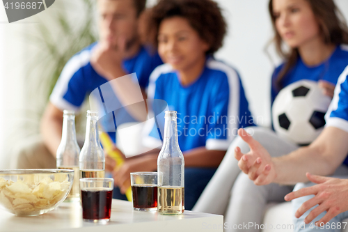 Image of football fans with drinks and chips at home