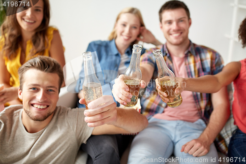 Image of happy friends drinking beer at home party