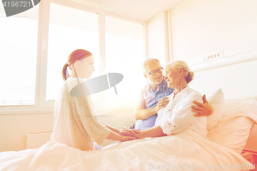 Image of happy family visiting senior woman at hospital