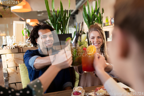 Image of happy friends clinking drinks at restaurant