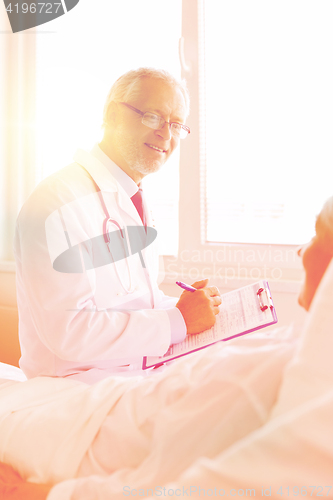 Image of senior woman and doctor with clipboard at hospital