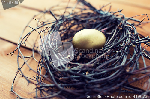 Image of close up of golden easter egg in nest on wood