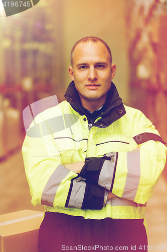 Image of man in coveralls with box at warehouse