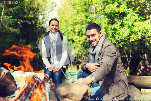 Image of happy couple roasting marshmallow over camp fire