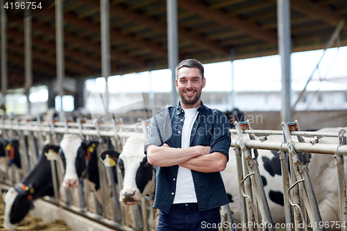 Image of man or farmer with cows in cowshed on dairy farm