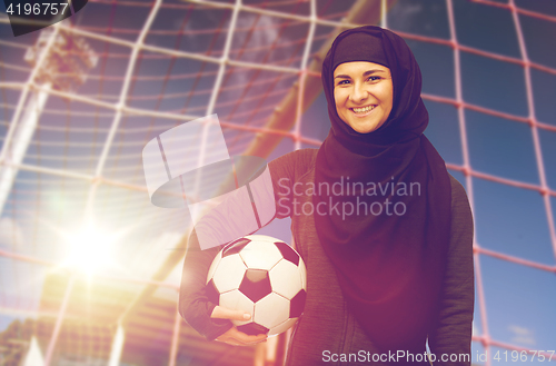 Image of happy muslim woman in hijab over football goal