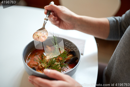 Image of woman eating seafood soup at restaurant