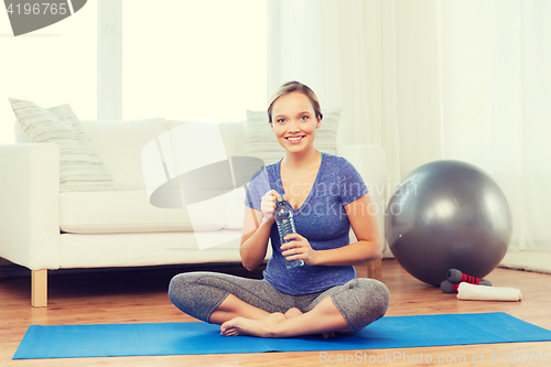 Image of happy woman with water bottle exercising at home