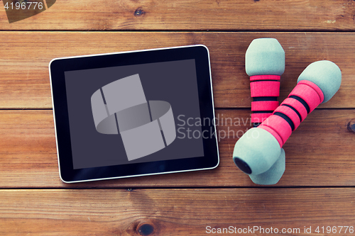 Image of close up of dumbbells and tablet pc on wood