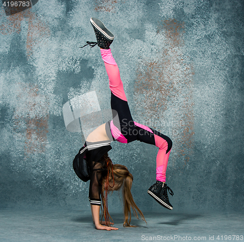 Image of Young girl break dancing on wall background.