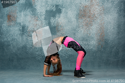 Image of Young girl break dancing on wall background.