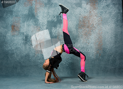 Image of Young girl break dancing on wall background.