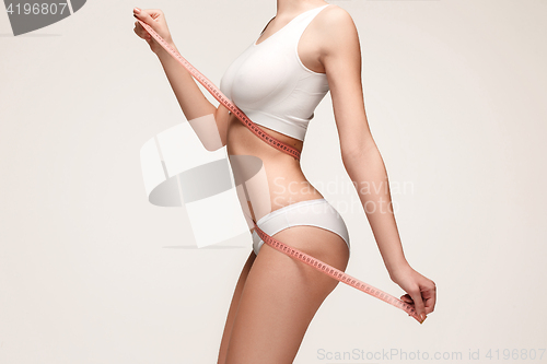 Image of The girl taking measurements of her body, white background.