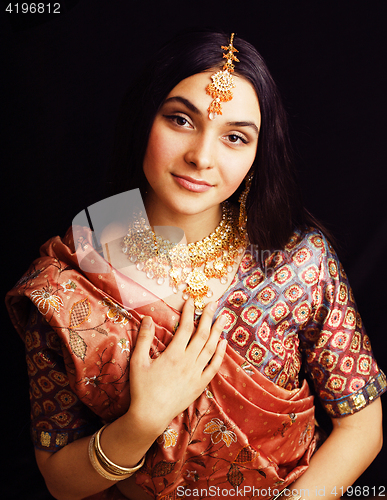 Image of beauty sweet real indian girl in sari smiling on black background, jewelry shining 